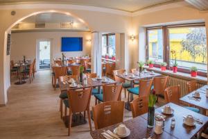 ein Speisesaal mit Tischen und Stühlen in einem Restaurant in der Unterkunft Ahorn Hotel in München