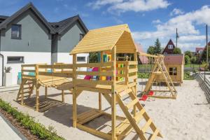 um parque infantil de madeira com uma estrutura de brincar em Domki Morskie Tarasy em Jastrzebia Gora