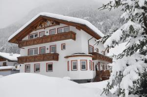 a house covered in snow with snow covered trees at Appartement Alpenrose in Imsterberg