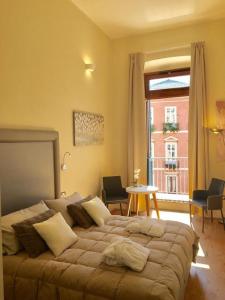 a bedroom with a bed and a table and a window at Antico Corso Charme in Cagliari