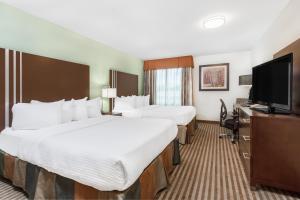 a hotel room with two beds and a flat screen tv at Ramada by Wyndham Carlyle in Carlyle