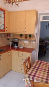 a kitchen with wooden cabinets and a table and a dining room at Nineta's House Sea View near the Airport in Artemida