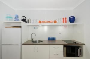 
a kitchen with white cabinets and white appliances at By The Sea Port Douglas in Port Douglas
