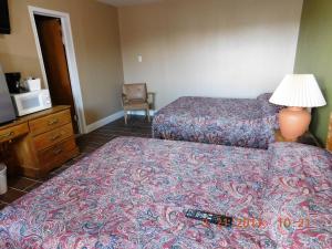 a hotel room with two beds and a lamp at American Star Inn in Munday