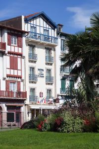 a large white building with balconies and a palm tree at Hotel Le Relais Saint-Jacques in Saint-Jean-de-Luz