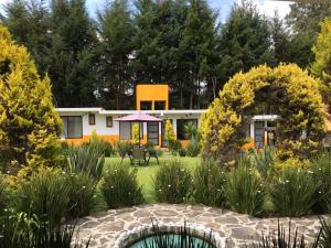 un jardín con una casa en el fondo en Hotel Finca los Girasoles, en Valle de Bravo