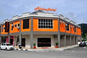 an orange building with a car parked in front of it at Aloha Hotel in Lumut