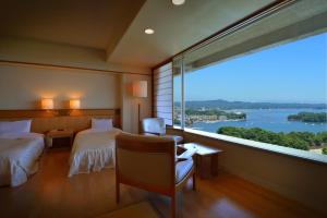 a hotel room with two beds and a large window at Hotel Matsushima Taikanso in Matsushima