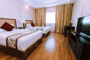 a hotel room with two beds and a flat screen tv at Palawan Uno Hotel in Puerto Princesa City