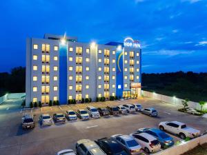 a hotel with cars parked in a parking lot at Hop Inn Ubon Ratchathani in Ubon Ratchathani