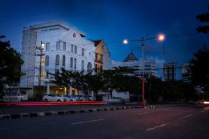 een stadsstraat 's nachts met een wit gebouw bij DeMira Hotel in Surabaya