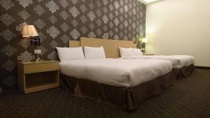 Habitación de hotel con 2 camas con sábanas blancas en Dreamer Hotel en Budai