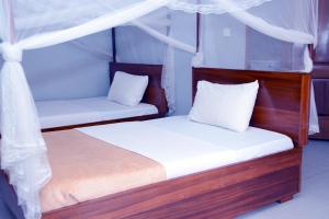 2 bedden in een kamer met witte lakens en kussens bij Jaguar Hotel Kampala in Kampala