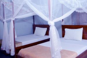 2 Betten mit weißen Vorhängen und weißen Kissen in der Unterkunft Jaguar Hotel Kampala in Kampala