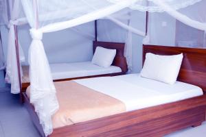 2 Betten in einem Zimmer mit weißen Kissen in der Unterkunft Jaguar Hotel Kampala in Kampala
