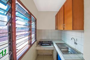 a kitchen with a stove and a sink and a window at RedDoorz Plus near Ciputra World Kuningan 2 in Jakarta