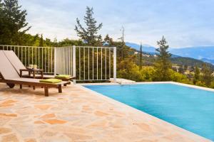 a swimming pool with a chaise lounge and a chair at Magganos Sunset Villas in Fiskardho