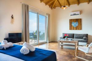 a bedroom with a bed and a living room with a balcony at Magganos Sunset Villas in Fiskardo