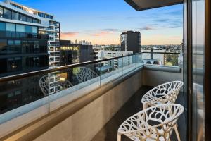 a balcony with two chairs and a view of the city at District South Yarra in Melbourne