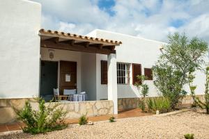 ein weißes Haus mit einer Terrasse davor in der Unterkunft Apartamentos Es Carnatge - Formentera Vacaciones in Playa Migjorn