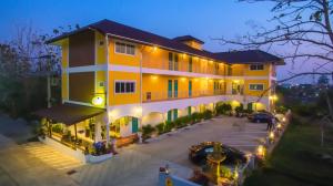 un gran edificio amarillo con coches aparcados en un aparcamiento en Baanlugchange Hotel en Chanthaburi