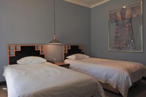 a bedroom with two beds and a painting on the wall at Willow Place Guest House in Midrand