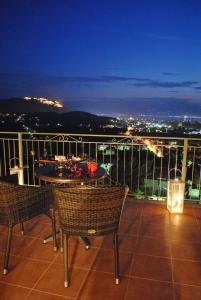 a balcony with two chairs and a table and lights at Iliothea in Nafplio