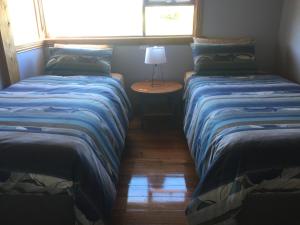 two beds in a room with a table and a window at Dolphin Beach House in Swansea