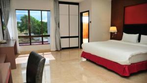 a bedroom with a large bed and a large window at The Centro Hotel & Residence By Orchardz in Batam Center