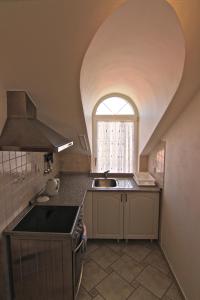 una cocina con fregadero y una ventana arqueada en Guest House Maxim, en Liptovský Mikuláš