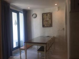 a dining room with a table and a clock on the wall at The Chelona pool access by Away in Hua Hin