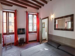 フィレンツェにあるIl Quartierino d'Oltrarnoの赤いカーテン、ベッド、鏡が備わるベッドルーム1室が備わります。