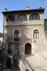 una antigua casa de piedra con tres ventanas y una puerta en Cal Vidal, en Mura