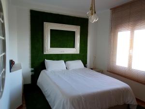 een slaapkamer met een wit bed en een groene muur bij Atico77 in Cáceres