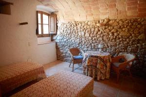 Zimmer mit einem Tisch, Stühlen und einer Steinmauer in der Unterkunft La Requisa in Pontós