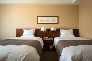 a hotel room with two beds and a table with a phone at Rembrandt Hotel Ebina in Ebina +22 photos