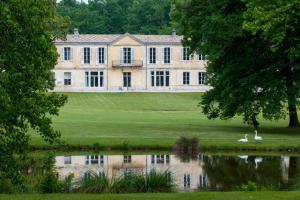 uma casa grande com dois cisnes em frente a um lago em Les Sources de Caudalie em Martillac