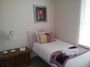 a small bedroom with a bed and a night stand at Casa Rossa - Barossa in Lyndoch