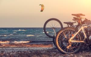 a bike parked on the beach with a kite in the sky at Keros Blue - Luxury in Wilderness in Kalliópi