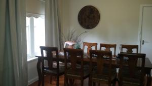 a dining room with a table with chairs and a clock on the wall at Casa Rossa - Barossa in Lyndoch