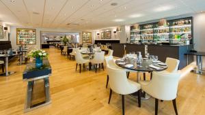 un restaurante con mesas y sillas blancas y un bar en The Park Hotel, en Barnstaple