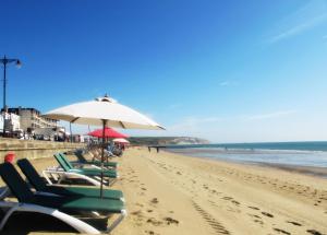 a row of beach chairs and an umbrella on a beach at Regent Court - Seafront, Sandown --- Car Ferry Optional Extra 92 pounds Return from Southampton in Sandown