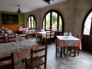 un comedor con mesas, sillas y ventanas en Posada La Ceña en Novales