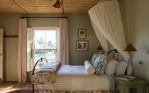 1 dormitorio con cama con dosel y ventana en Vredenhof Farm Cottage, en Elgin