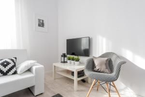 ein weißes Wohnzimmer mit einem Stuhl und einem TV in der Unterkunft P&O Apartments Andersa INTRACO in Warschau