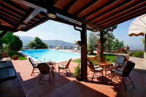 Un patio con mesa y sillas y una piscina. en Villa La Foce, en Castiglion Fiorentino