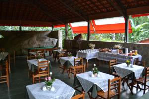 um restaurante com mesas brancas e cadeiras com flores em Pousada Canto do Curió Paraty em Paraty