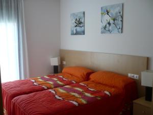 ein Schlafzimmer mit einem Bett mit einer orangefarbenen Bettdecke in der Unterkunft Apartaments Las Carolinas in Sant Carles de la Ràpita
