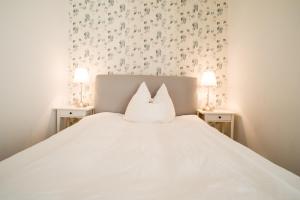 1 dormitorio con 1 cama blanca y 2 mesitas de noche en Weddeler Hof, en Cremlingen