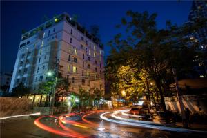 a city street at night with a tall building at Sabai Sathorn Service Apartment in Bangkok